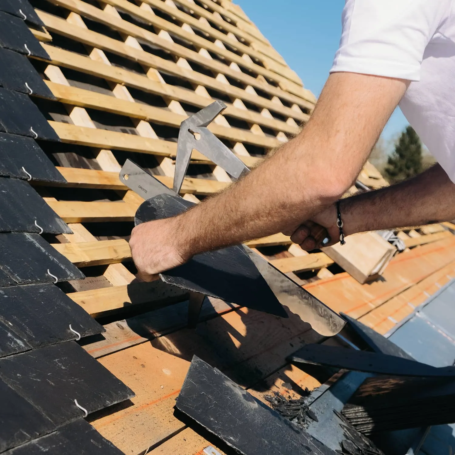 Couvreur travaillant une couverture en ardoise avec ses outils