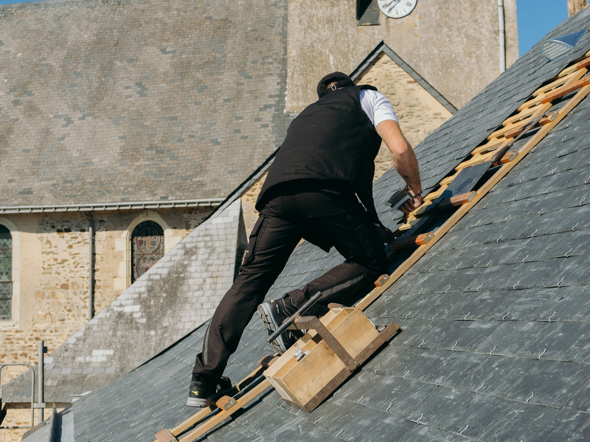 Artisan couvreur travaillant sur un toit d'un batiment ancien traditionnel