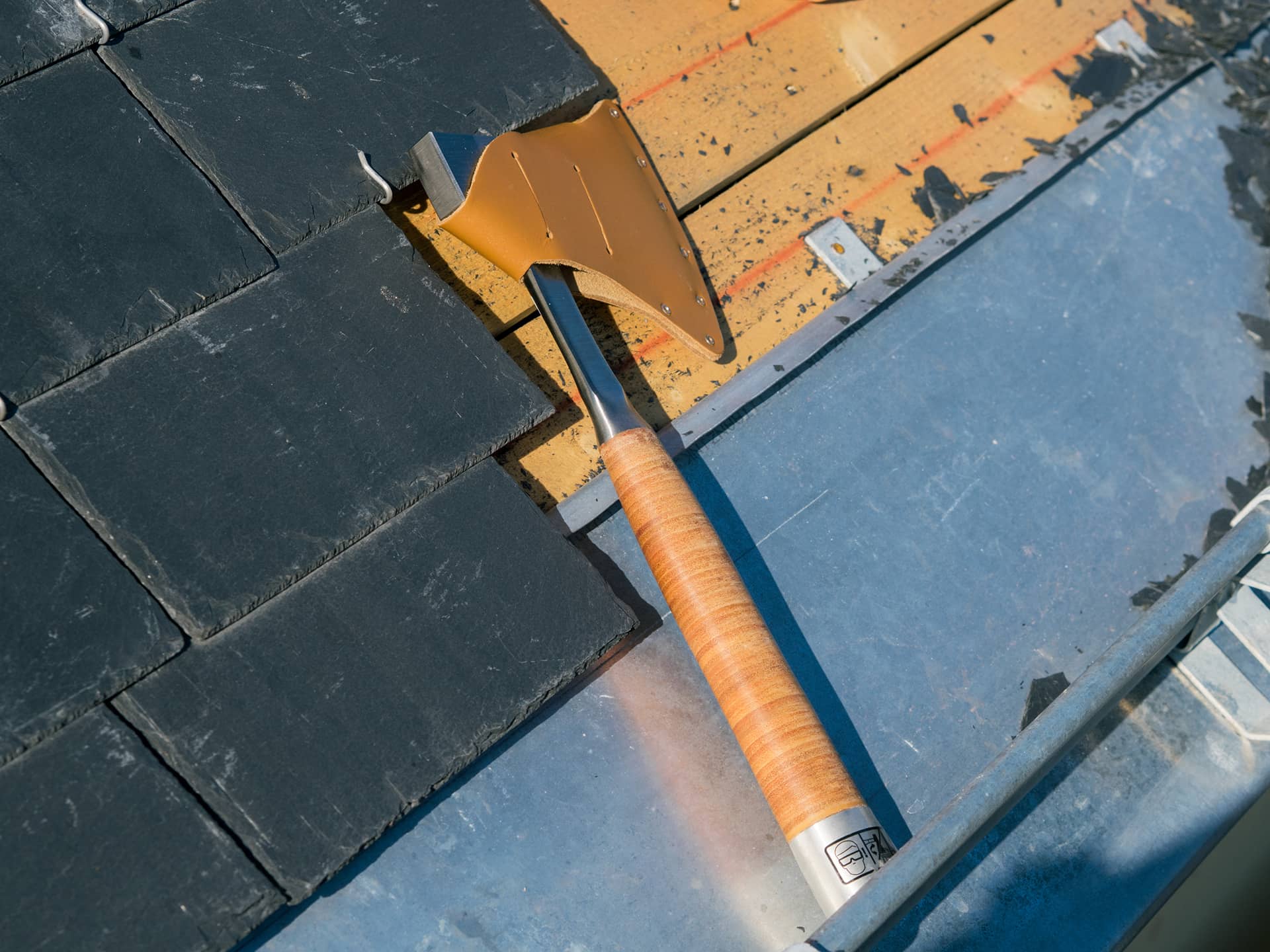 Hachette de couvreur sur un toit avec des ardoises posée sur du zinc