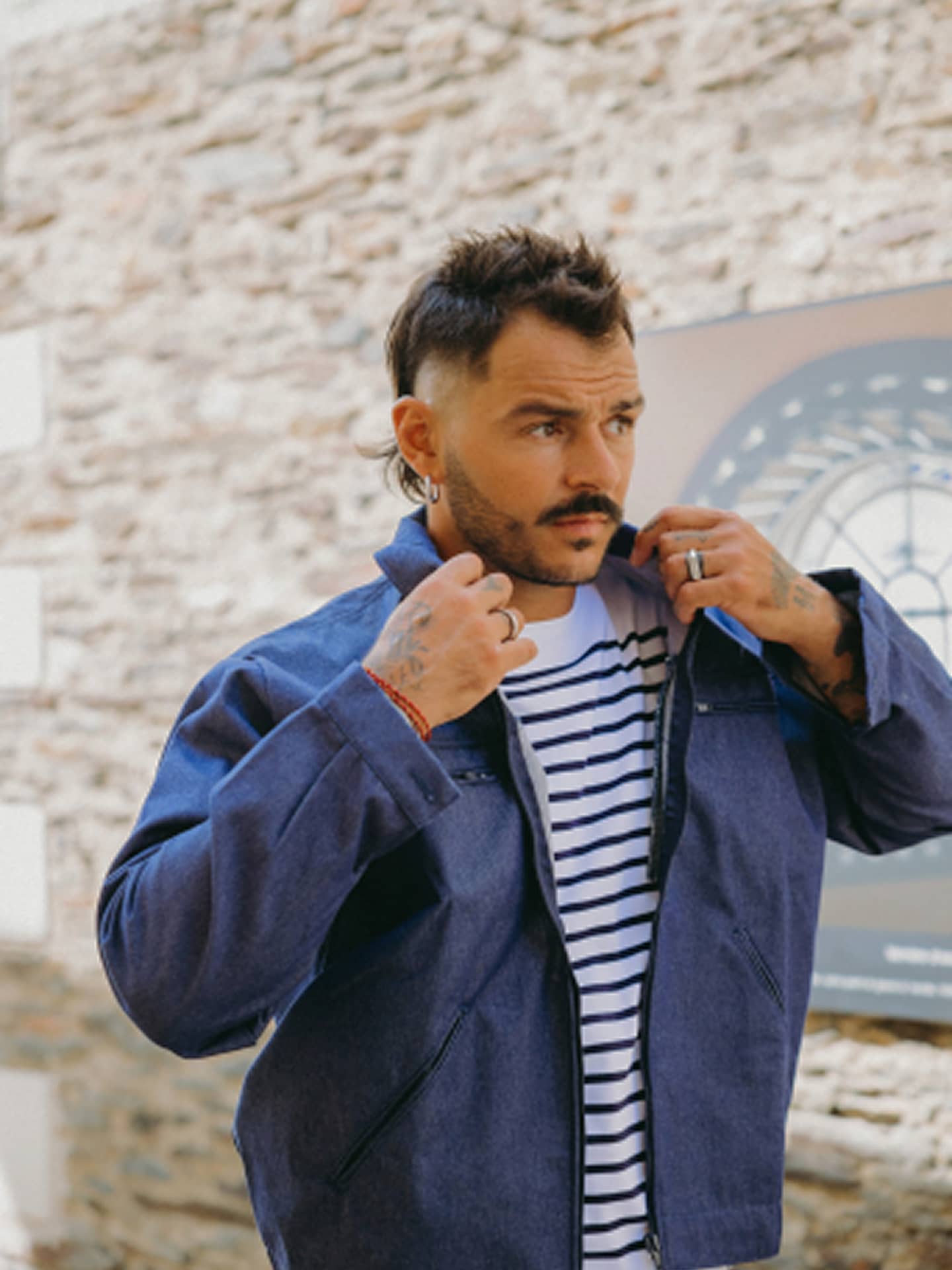 Robin Gaborit ajustant le col du blouson bleu en grisette Le Laboureur porté sur une marinière